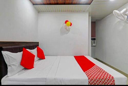 a bedroom with a bed with red and white pillows at Hotel The mid town inn in Patna