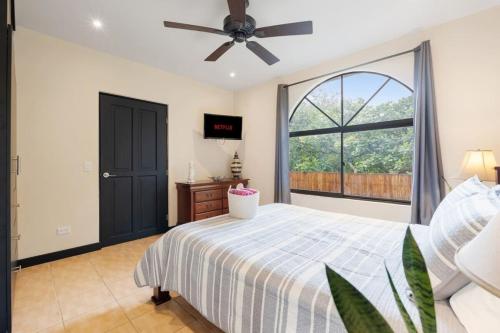 a bedroom with a bed with a ceiling fan and a window at Suite 3 Jaguar - Beach & Pool 2 BR Condo in Brasilito