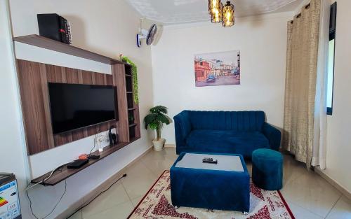 a living room with a blue couch and a tv at Lovana Apartments and Hotel in Gulu