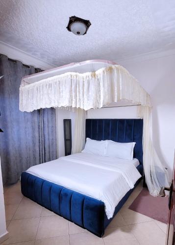 a bedroom with a large bed with a blue headboard at Lovana Apartments and Hotel in Gulu