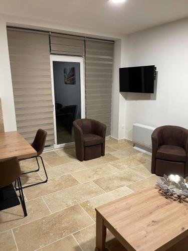 a living room with chairs and a table and a flat screen tv at Lepigeonnier de Papy in Dijon