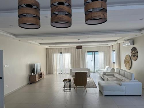 Una sala de estar con un sofá y un televisor. en Villa Prestige Somone, en Somone