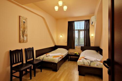 Habitación con 2 camas, silla y ventana en Family Hotel Marsina en Sofía