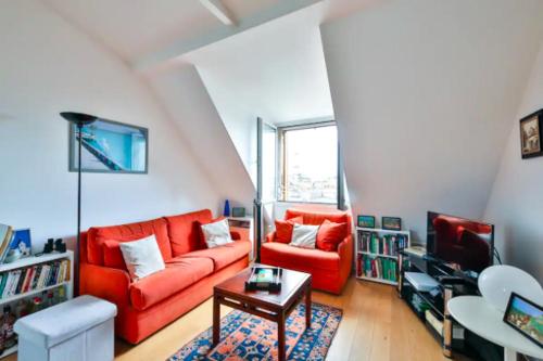 un salon avec un canapé rouge et une table dans l'établissement Les Toits de Paris Rue Cler Vue Tour Eiffel, à Paris