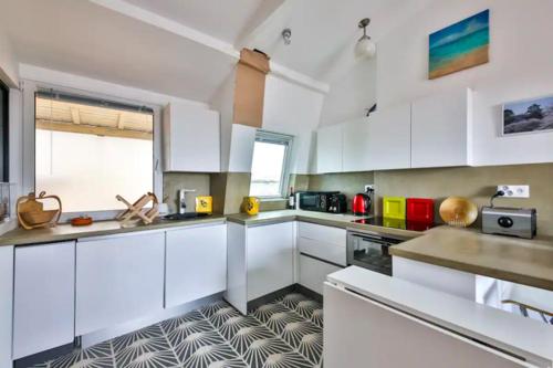 une grande cuisine avec des armoires blanches et une fenêtre dans l'établissement Les Toits de Paris Rue Cler Vue Tour Eiffel, à Paris