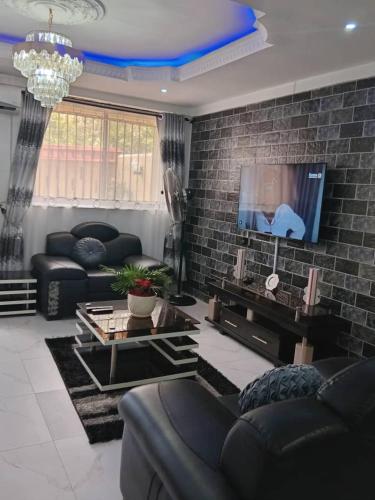 a living room with a couch and a tv at Home Away from Home - Gowon Estate near Gemade, Ipaja, Lagos in Lagos