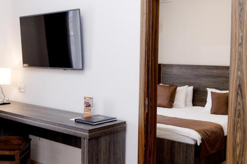 a hotel room with a bed and a television at Infinity Plaza Hotel in Atyraū