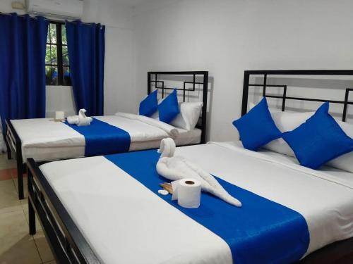 a bedroom with three beds with blue and white pillows at Arthur Holiday Inn in Legazpi