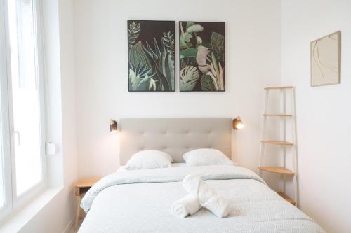 - une chambre blanche avec un lit et 2 serviettes blanches dans l'établissement Le petit joyau de Voltaire, à Saint-Quentin