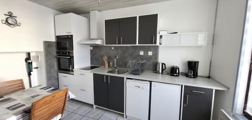 une cuisine avec des armoires blanches et des appareils noirs dans l'établissement Cap en vue, à Fécamp