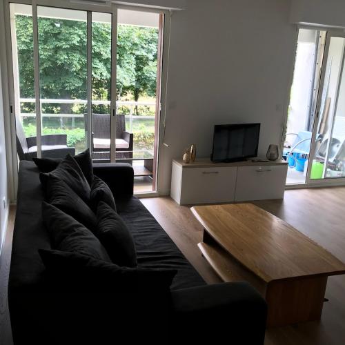 un salon avec un canapé noir et une télévision dans l'établissement VANNES Le PORT RCL, à Vannes