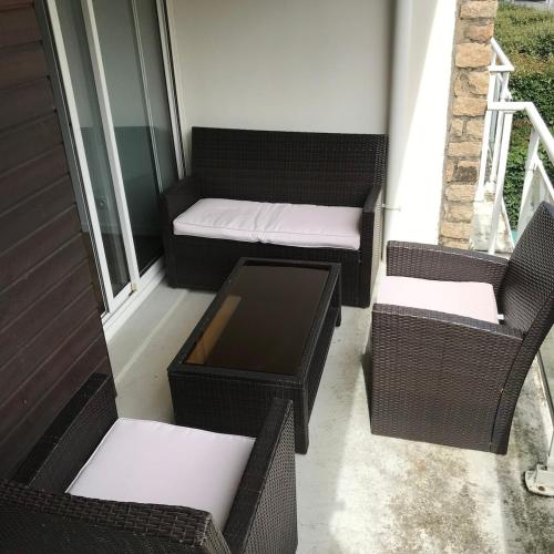 une terrasse couverte avec des chaises en osier, un banc et une table dans l'établissement VANNES Le PORT RCL, à Vannes