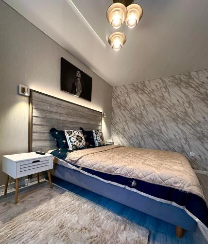 a bedroom with a king sized bed and a night stand at GOLD Apartment - Tomis Nord in Constanţa