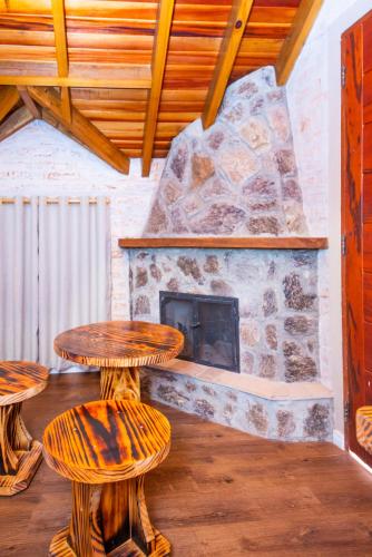 a room with two tables and a stone fireplace at Pousada Alpes da Mantiqueira in Monte Verde