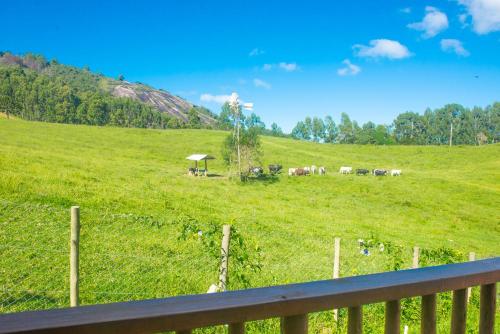 a field with a fence and horses in a field at Pousada Alpes da Mantiqueira in Monte Verde