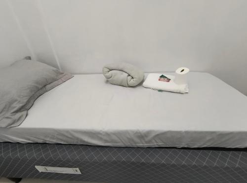 a white bed with a towel and a roll of paper at kitnet Próximo ao Metro Conceição in Sao Paulo