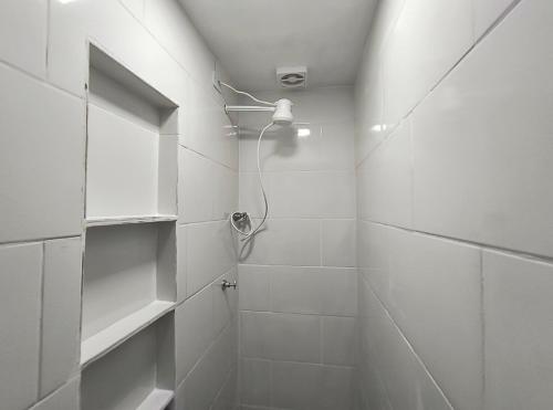 a white bathroom with a shower with a shower at kitnet Próximo ao Metro Conceição in Sao Paulo