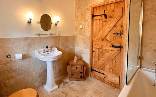 a bathroom with a sink and a wooden door at 1 Swollowholm Cottage in Richmond