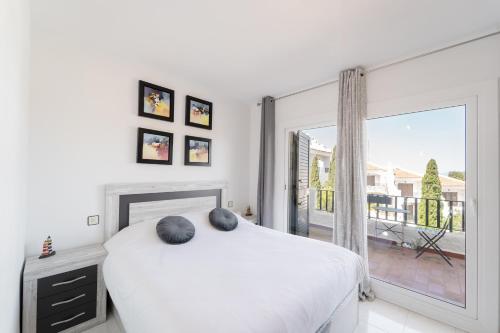 a white bedroom with a bed and a large window at WELCS CASA ADOSADA 215 EMP con piscina comunitaria in Roses