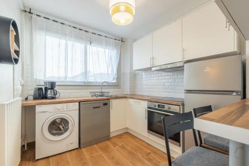 une cuisine avec des armoires blanches et une laveuse et une sécheuse dans l'établissement Cozy 5 chambres 10 pers, à Toulouse