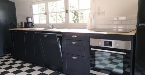 une cuisine avec un évier et une cuisinière dans l'établissement Maison à 250m de la mer au calme sous les pins, à Bretignolles-sur-Mer