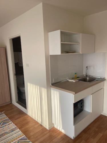 a white kitchen with a sink and a counter at lumpini ville sukhumvit 101 in Bangna