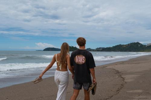 a man and a woman walking on the beach at Suite 4 Sloth - Pool&Beach 3 BR Condo in Brasilito