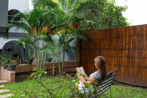 a girl sitting on a bench reading a book at Suite 4 Sloth - Pool&Beach 3 BR Condo in Brasilito