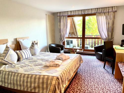 a hotel room with a bed and a large window at Hotel Restaurant Le Petit Kohlberg in Lucelle