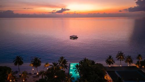 a sunset over the ocean with a dock in the water at Sirru Fen Fushi Private Lagoon Resort Maldives in Shaviyani Atoll