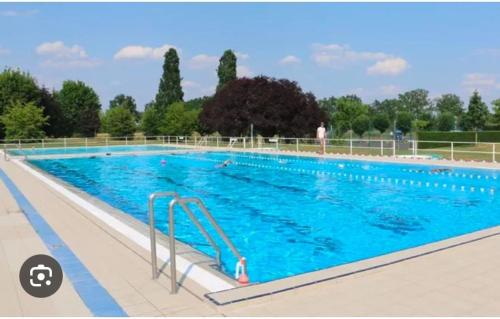 une grande piscine avec des gens dans l'eau dans l'établissement La Clémendière, un paradis caché, à Chailly-en-Gâtinais