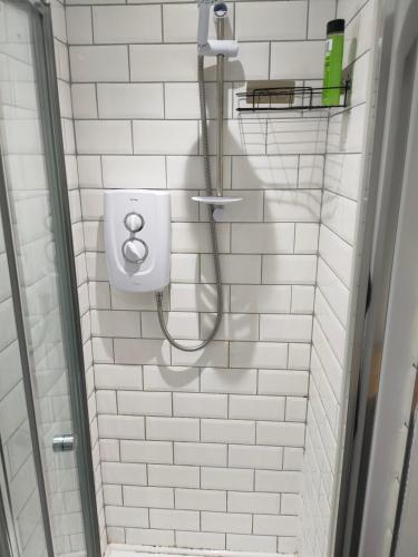 a white tiled bathroom with a shower and a toilet at Lovely Double Bedroom in Liverpool