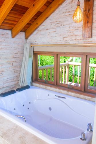 a large white tub in a room with a window at Pousada Alpes da Mantiqueira in Monte Verde