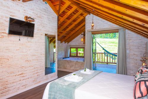 a bedroom with a bed and a large window at Pousada Alpes da Mantiqueira in Monte Verde