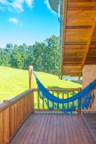 a porch with a blue hammock on a house at Pousada Alpes da Mantiqueira in Monte Verde