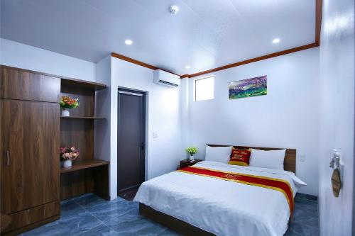a bedroom with a large bed and a cabinet at Khách sạn Tiến Đạt in Mèo Vạc