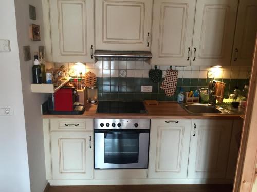 eine Küche mit weißen Schränken und einem Herd mit Backofen in der Unterkunft Luxury panoramic apartment Plan de Corones in Welsberg-Taisten