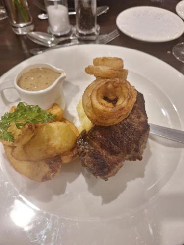 a plate of food with onion rings and dipping sauce at Carrygerry Country House in Shannon