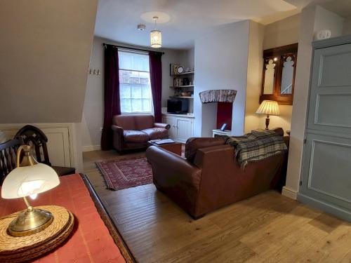 a living room with a brown couch and a chair at 7 Monk Bar Court YORK in York