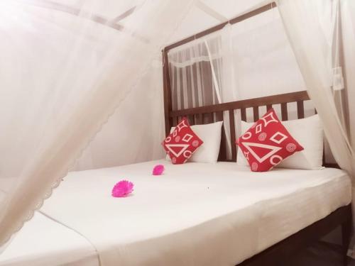 a bed with red and white pillows on it at Mountain Heaven inn in Mirissa