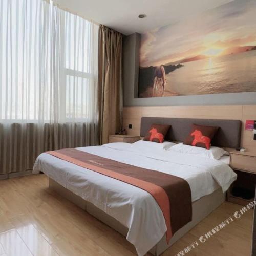 a bedroom with a large bed with a painting on the wall at Junyi Hotel - Zaozhuang High Speed Railway Station in Taozhuang