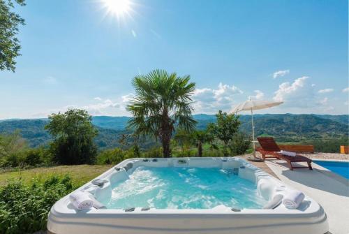 a hot tub in a yard with a chair and an umbrella at Villa Sussini in Central Istria for 8 people with jacuzzi & pet friendly in Krbune