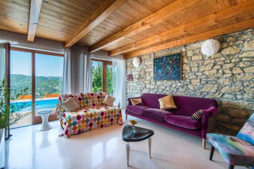 a living room with a purple couch and a stone wall at Villa Sussini in Central Istria for 8 people with jacuzzi & pet friendly in Krbune
