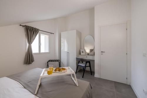a white bedroom with a bed and a table with food on it at La Grande Bellezza 1 in Lastovo