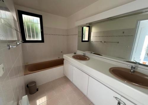 une salle de bain avec deux lavabos et un grand miroir dans l'établissement Appartement Hauts de Vaugrenier, à Villeneuve-Loubet