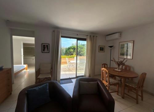 d'un salon avec une table, des chaises et une porte coulissante en verre. dans l'établissement Appartement Hauts de Vaugrenier, à Villeneuve-Loubet