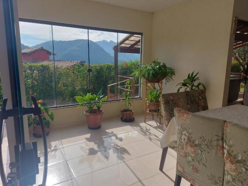 a balcony with plants and a table and a window at Temporada no Paraíso em Teresópolis in Teresópolis