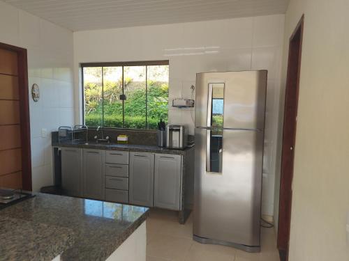 a kitchen with a stainless steel refrigerator and a window at Temporada no Paraíso em Teresópolis in Teresópolis