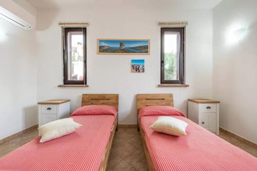 two beds in a room with two windows at Villa La Fata in Cuile Pazzoni