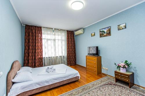 a bedroom with a bed and a tv and a window at Однушка в центре Алматы, до Арбата 5 минут ходьбы #82 in Almaty